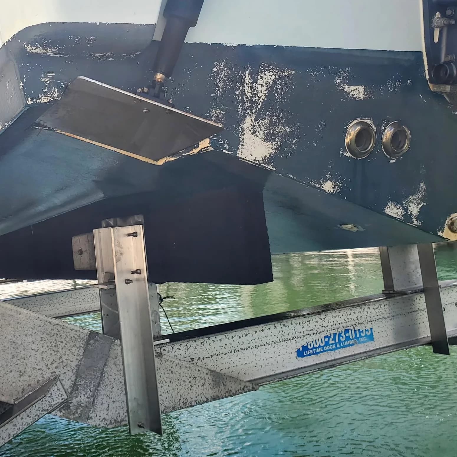 Boat hull resting on black lift bunks with adjustable metal supports