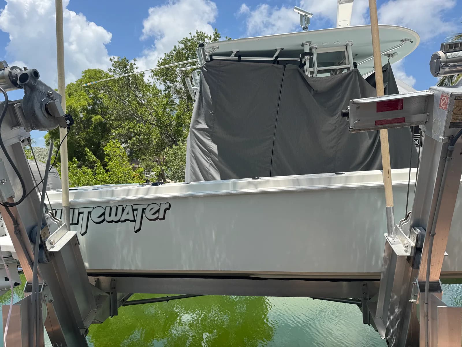 A center-console boat supported on a lift beside the dock