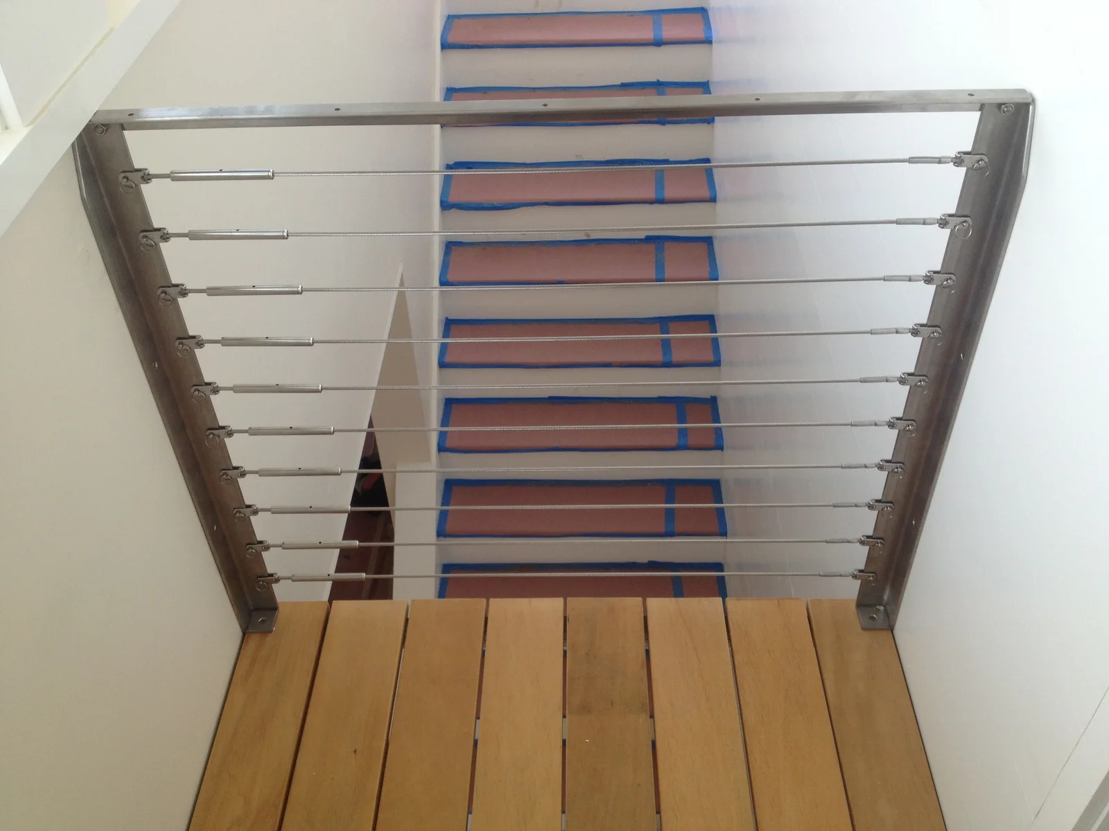 Metal posts and horizontal cable railing at an interior stair landing