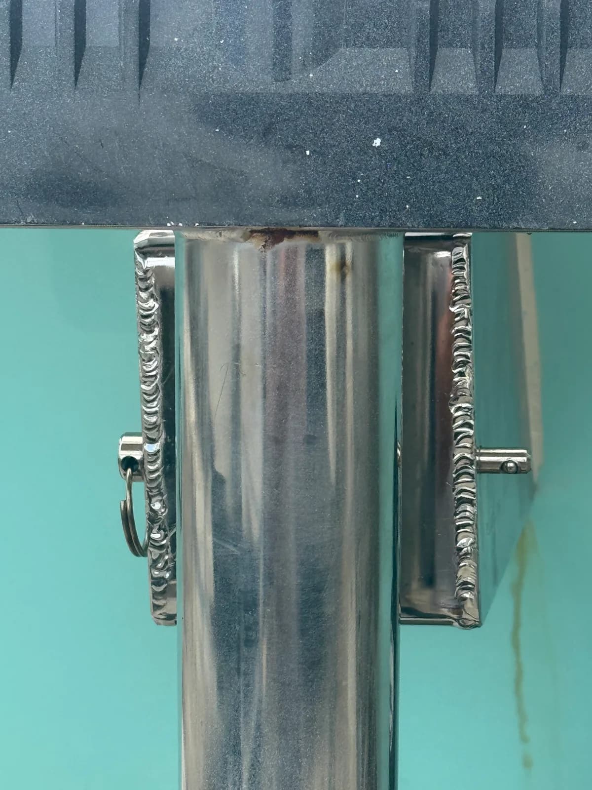 Close-up of weld beads joining a polished metal bracket to a tube