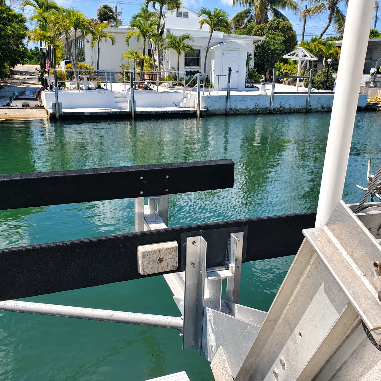 Black boat lift bunks and metal supports above a canal